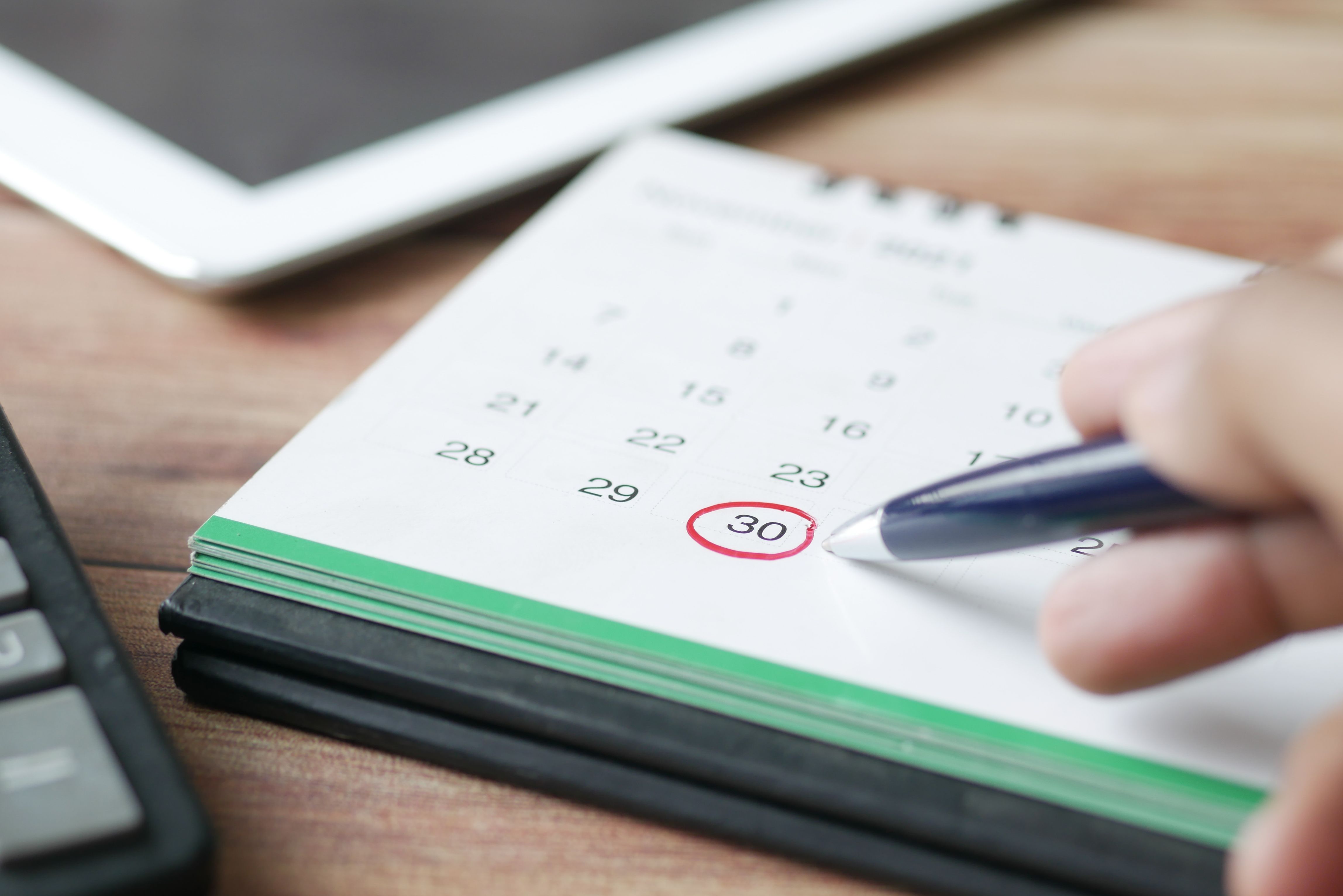 Deadline circled on a desk calendar, with a pen pointing at the circle